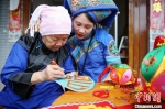 黄肖琴(左)在教徒弟赵爱培制作绣球。　曾开宏 摄 - 西安网