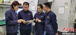 图为何小虎(左二)与同事交流工作。　受访者供图 - 陕西新闻
